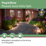 Warm white garden path lights along brick house creating atmospheric terrace and garden lighting