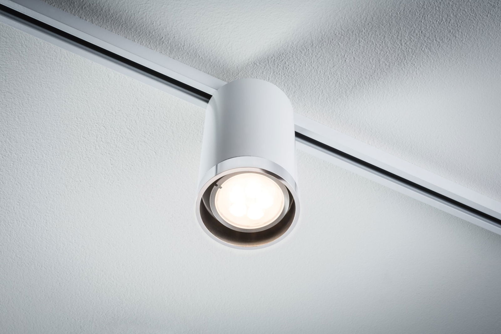 Weißer LED-Deckenstrahler aus Metall an Schienensystem für moderne Innenbeleuchtung