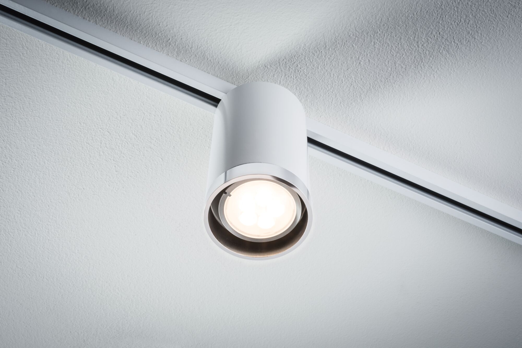 Weißer LED-Deckenstrahler aus Metall an Schienensystem für moderne Innenbeleuchtung