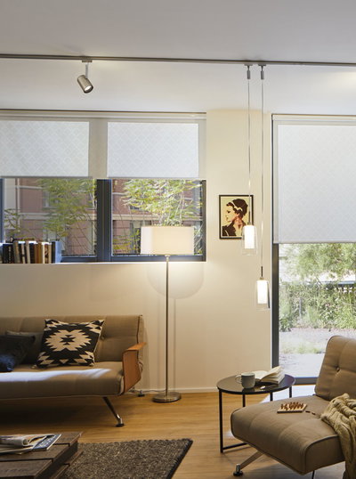 Salon moderne avec canapé gris, lampe sur pied en métal et deux suspensions en verre.