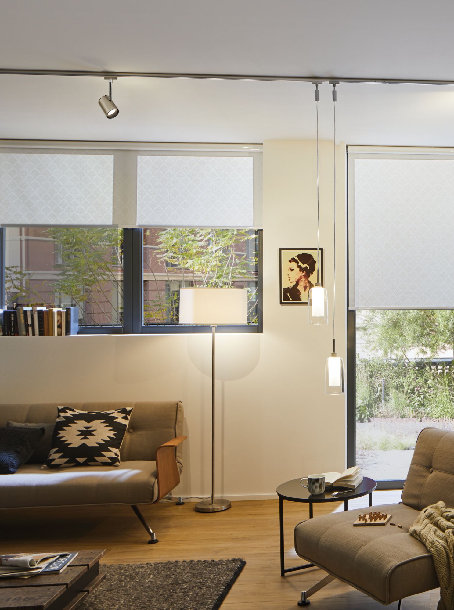 Modern living room with grey sofa, metal floor lamp, and two hanging glass pendant lights.