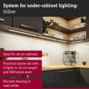 Matte white under-cabinet light installed under dark kitchen cabinets with wooden shelf and coffee machine