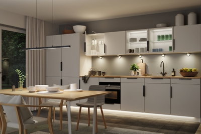 Moderne Küche mit grauen Schränken, Holzarbeitsplatte und LED-Unterbauleuchten für stimmungsvolle Beleuchtung