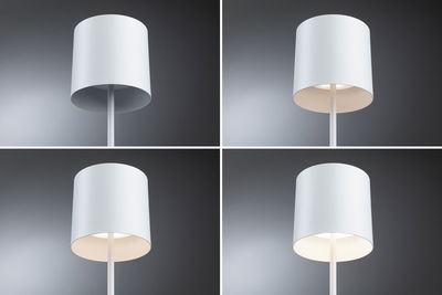 Vier witte metalen vloerlampen met cilindervormige kap tegen grijze achtergrond, verschillende lichtsterktes