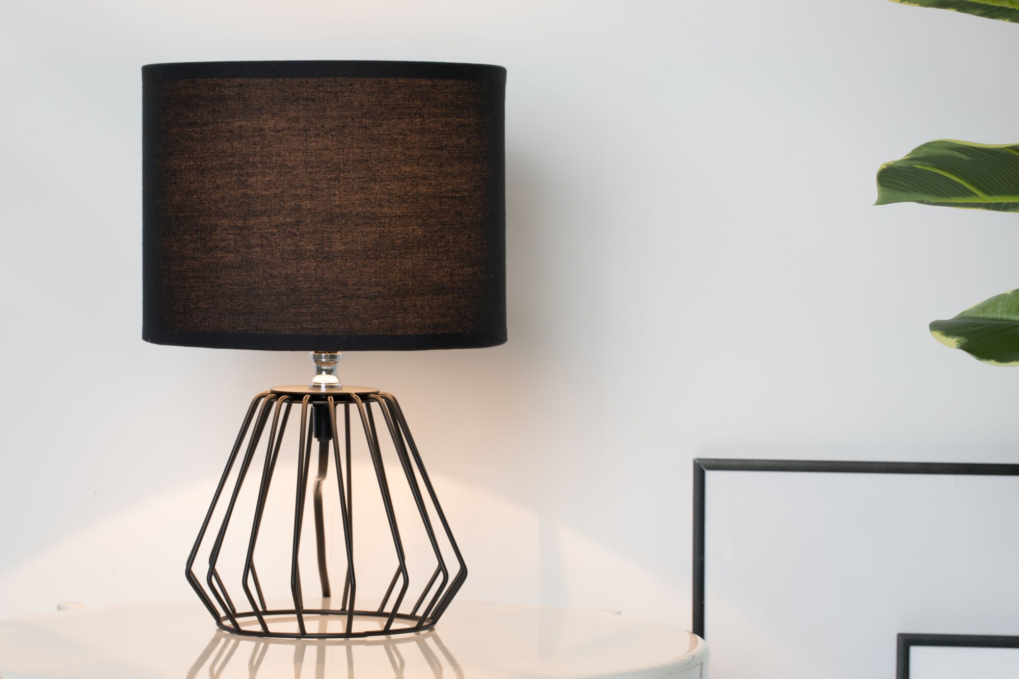 Lampe de table moderne avec abat-jour en tissu noir et structure métallique géométrique pour un éclairage élégant.
