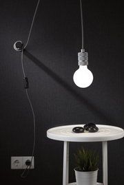 Hanging light bulb with grey metal socket and black cord against dark background, modern lighting design