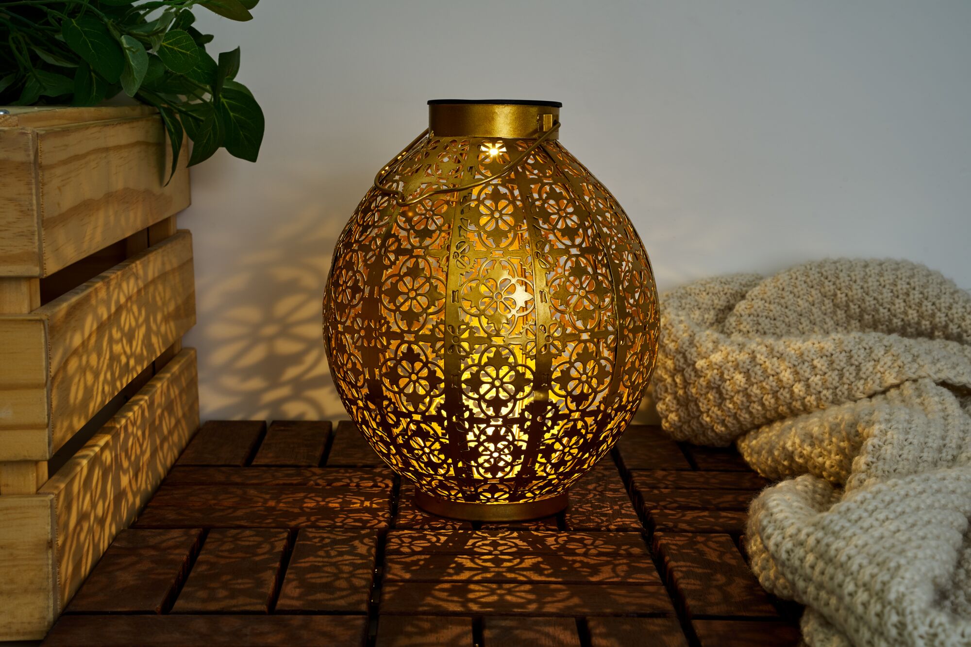 Goldfarbene Metalllaterne mit filigranem Blumenmuster und warmem Licht für stimmungsvolle Dekoration.