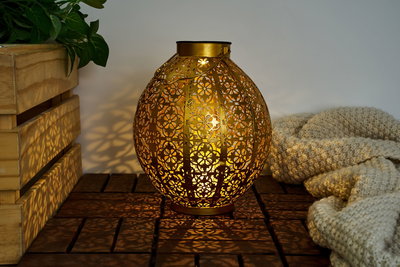 Gold metal lantern with intricate floral pattern and warm light for cozy decorative ambiance.