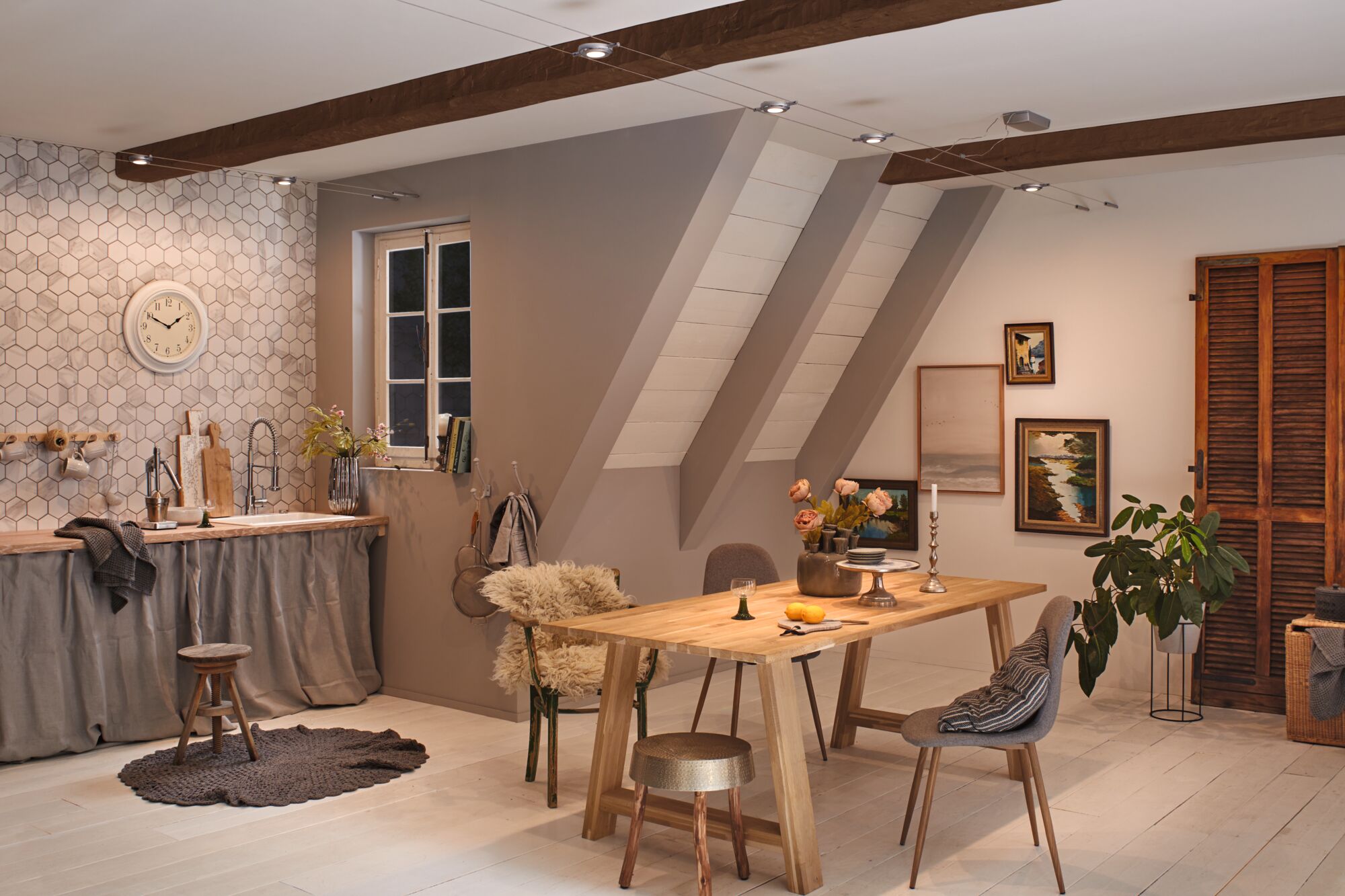 Gezellige woonkeuken met houten tafel, grijze stoelen en moderne kabelverlichting met LED-spots.