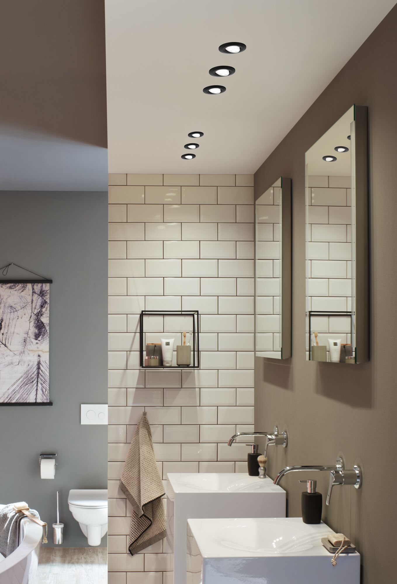 Modernes Badezimmer mit weißen Keramikwaschbecken, Wandarmaturen und schwarzen LED-Einbaustrahlern.