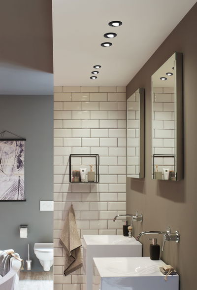 Modernes Badezimmer mit weißen Keramikwaschbecken, Wandarmaturen und schwarzen LED-Einbaustrahlern.