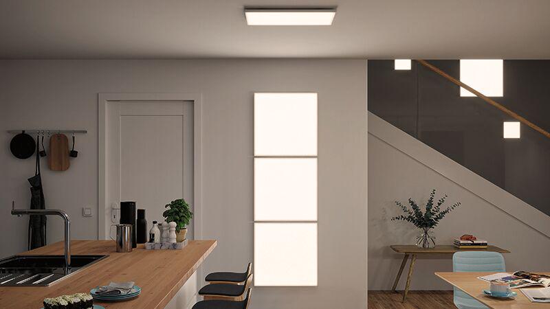 Salon moderne avec panneaux LED rectangulaires au plafond et au mur diffusant une lumière blanc chaud.