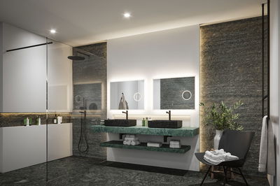 Modernes Badezimmer mit grünem Marmorwaschtisch, schwarzen Becken und LED-beleuchteten Spiegeln