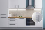 Cuisine moderne blanche avec plan de travail en bois, hotte en acier inoxydable et éclairage LED sous meuble.
