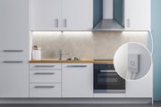 Cuisine blanche moderne avec plan de travail en bois, hotte en acier inoxydable et éclairage LED sous meuble avec interrupteur