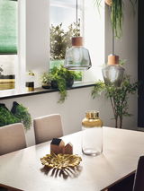 Modern dining area with two glass pendant lights and gold decor on light wood table in urban style