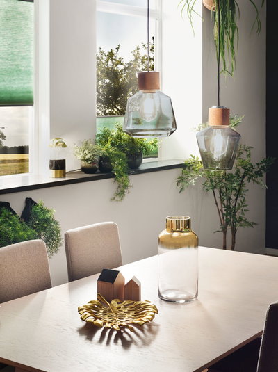 Modern dining area with two glass pendant lights and gold decor on light wood table in urban style