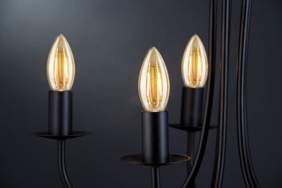 Schwarze Metall-Kerzenleuchter mit warmweiß leuchtenden Glühbirnen für stimmungsvolle Beleuchtung