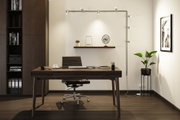 Modernes Büro mit dunklem Holztisch, schwarzem Lederstuhl und minimalistischer Wandbeleuchtung