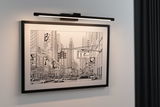 Black metal LED picture light illuminating urban black and white cityscape with cars and skyscrapers.