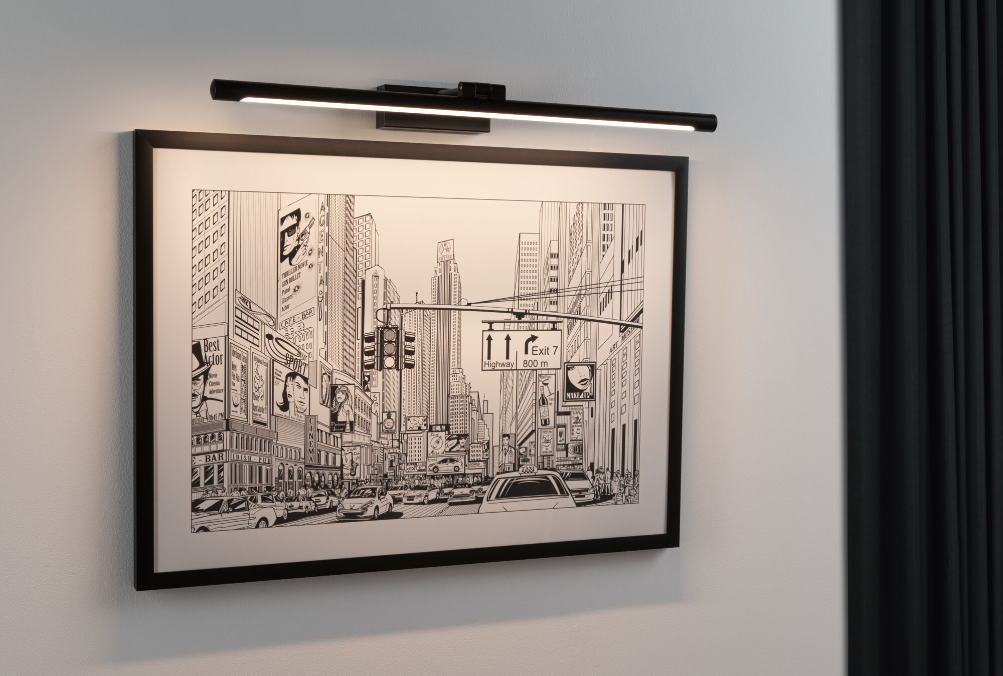 Black metal LED picture light illuminating urban black and white cityscape with cars and skyscrapers.