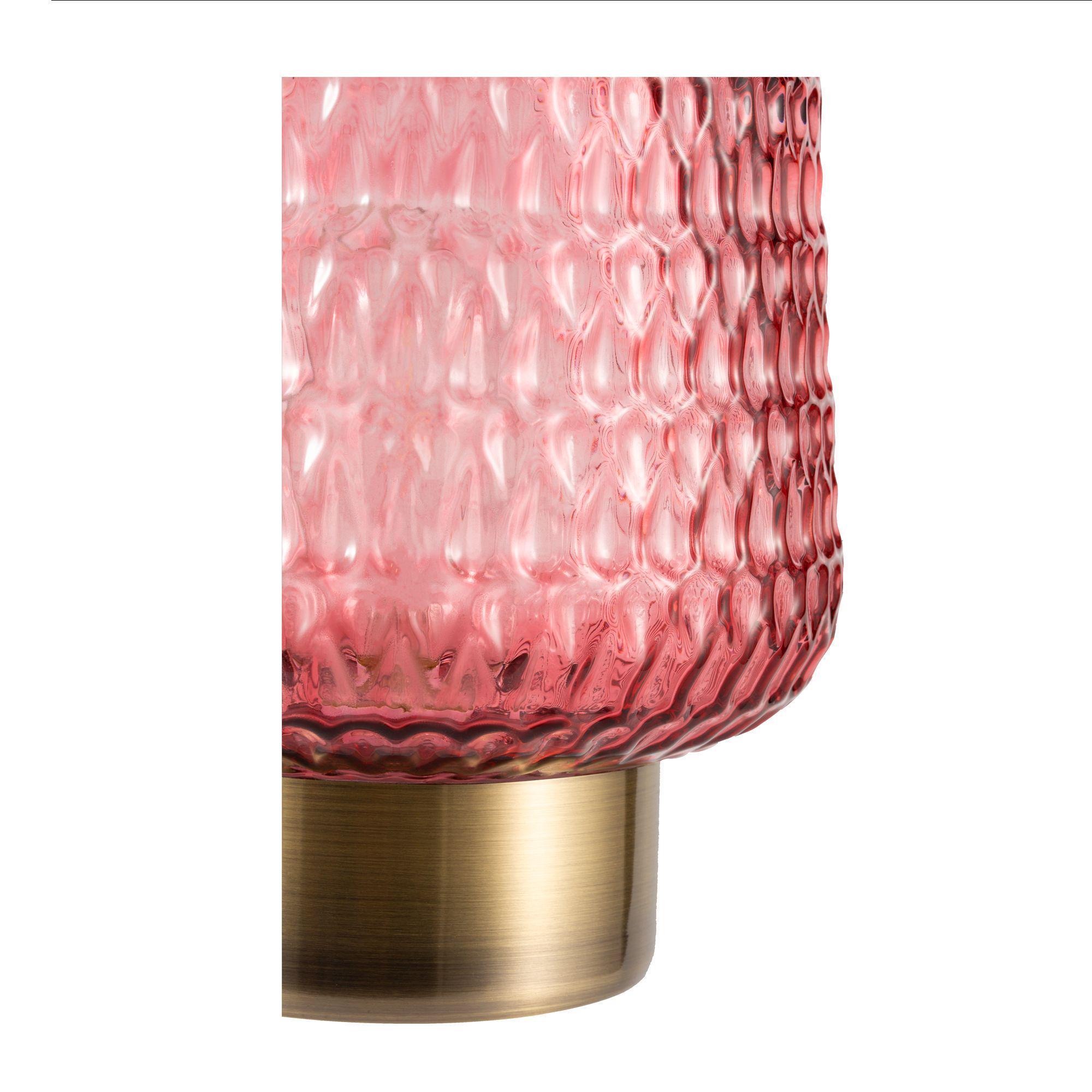 Close-up of red textured glass lampshade with brass-colored metal base for ambient lighting