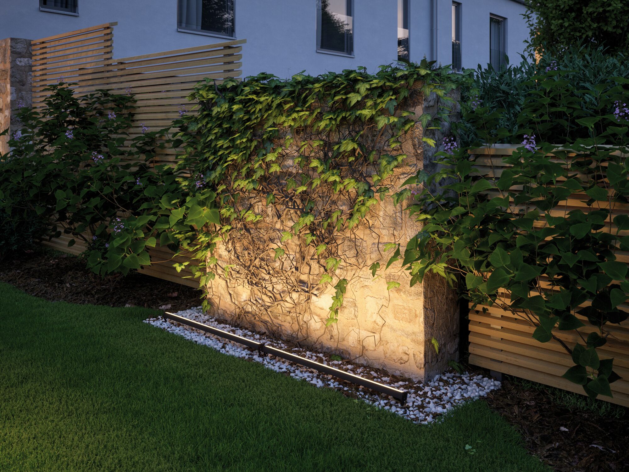 Schwarze LED-Bodenleuchte beleuchtet Steinmauer mit Efeu im Garten, moderne Außenbeleuchtung.