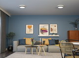 Modernes Wohnzimmer mit grauem Sofa, blauen Wänden und zwei runden Holz-Couchtischen mit Kerzen.