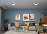 Modernes Wohnzimmer mit grauem Sofa, blauen Wänden und zwei runden Holz-Couchtischen mit Kerzen.