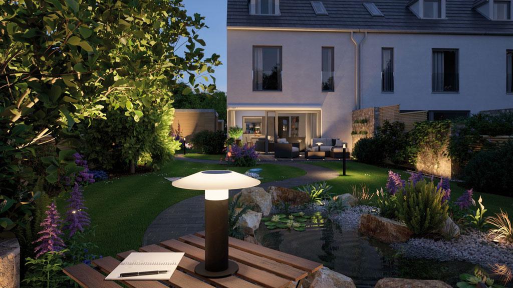Moderne Gartenleuchte mit weißem Lampenschirm und schwarzem Ständer beleuchtet Teich und Sitzbereich bei Abenddämmerung