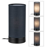 Cylindrical table lamp with black fabric shade and metal base for ambient lighting in interiors