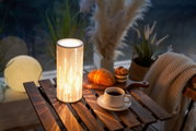 White metal LED table lamp with leaf pattern on wooden table beside coffee and pastry