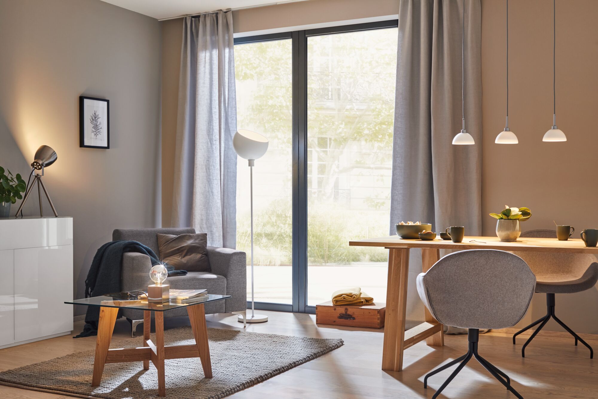 Salon moderne avec fauteuil gris, table en bois, table basse en verre et suspensions élégantes