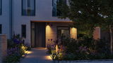 Modernes Haus mit Holzverkleidung und warmweißer Außenbeleuchtung im Gartenweg und Eingangsbereich
