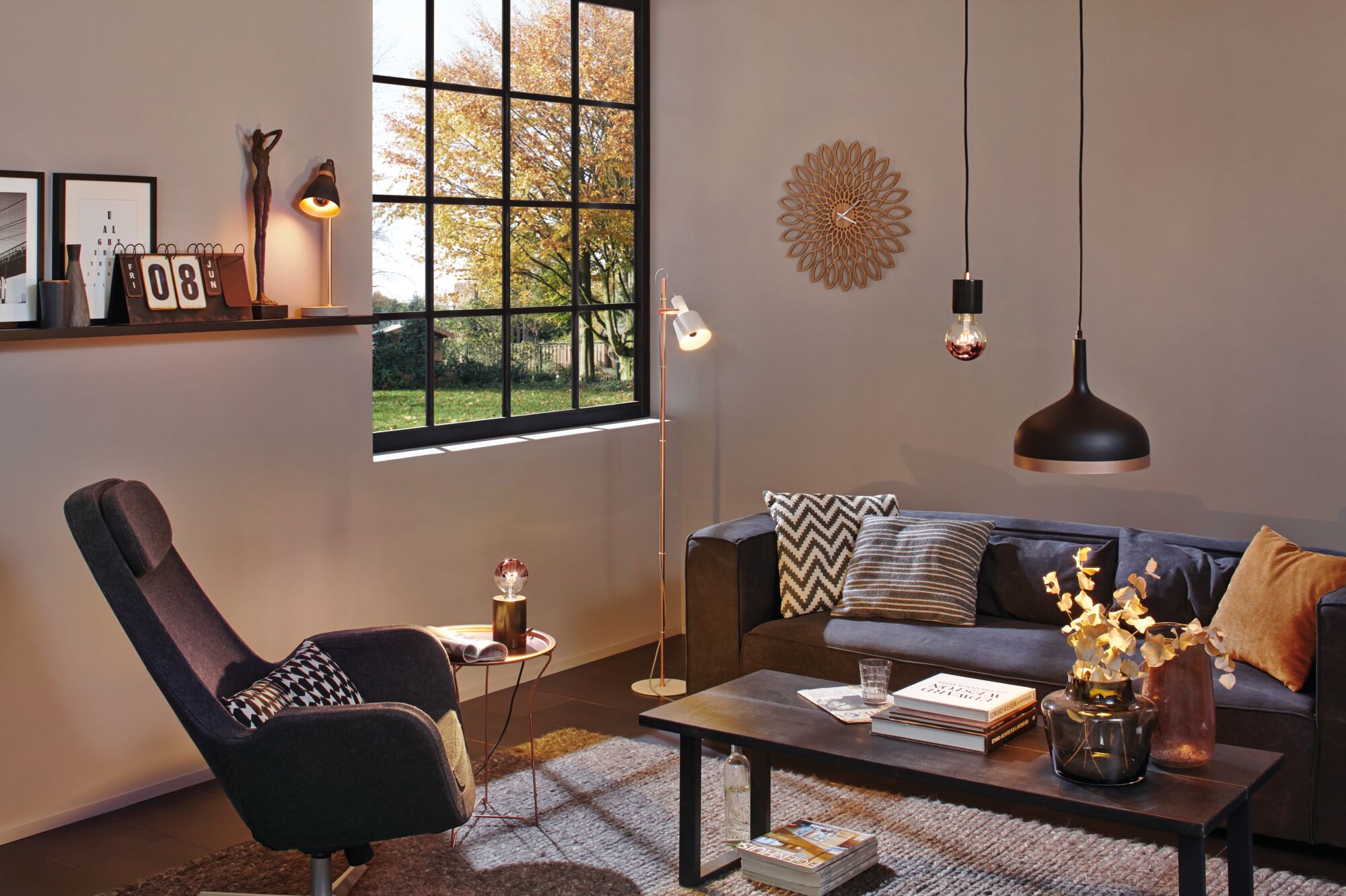 Modern living room with grey sofa, black pendant lights, and cozy reading chair in Scandinavian style