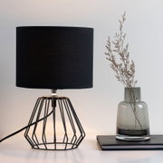 Lampe de table moderne avec abat-jour en tissu noir et structure métallique géométrique pour un éclairage élégant.