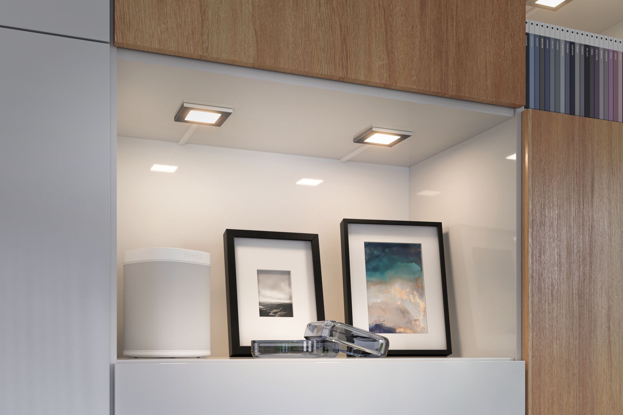 Éclairage LED blanc moderne sous meuble de cuisine avec enceinte et cadres photo.