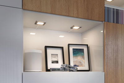 Éclairage LED blanc moderne sous meuble de cuisine avec enceinte et cadres photo.