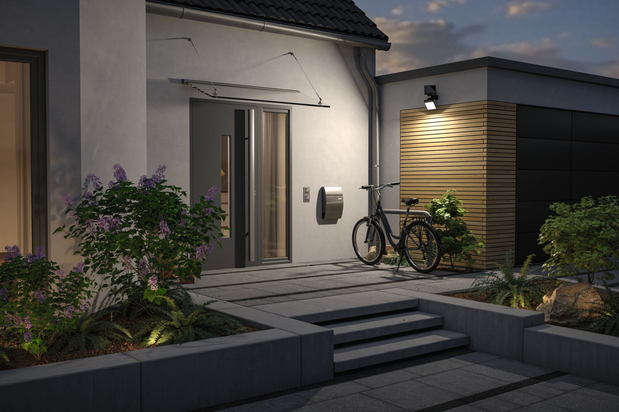 Modern house entrance with grey door, bicycle and outdoor wall light emitting warm white light at dusk