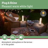 Cozy terrace with warm white Plug & Shine LED outdoor lighting and rattan furniture in garden