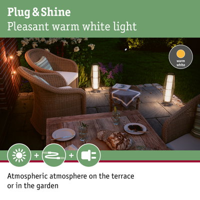Cozy terrace with warm white Plug & Shine LED outdoor lighting and rattan furniture in garden