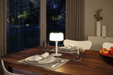 Modern white table lamp with warm white light on wooden table near set dining area and apples