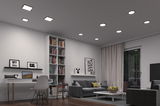 Salon moderne avec plafonniers LED blancs et canapé gris, éclairage d'ambiance élégant.