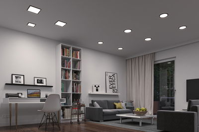 Salon moderne avec plafonniers LED blancs et canapé gris, éclairage d'ambiance élégant.