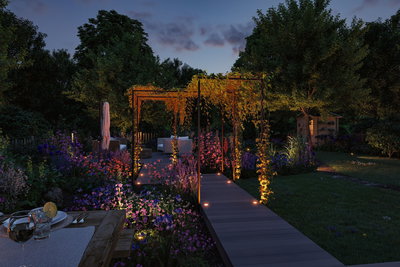 Allée de jardin éclairée avec spots LED encastrés et treillis dans un jardin vert au crépuscule