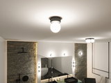 Rund loftlampe med hvidt glas og sort metalramme i moderne badeværelse med spejl og vask.
