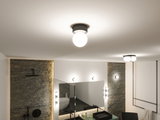 Ronde plafondlamp met wit glas en zwart metalen frame in moderne badkamer met spiegel en wastafel.