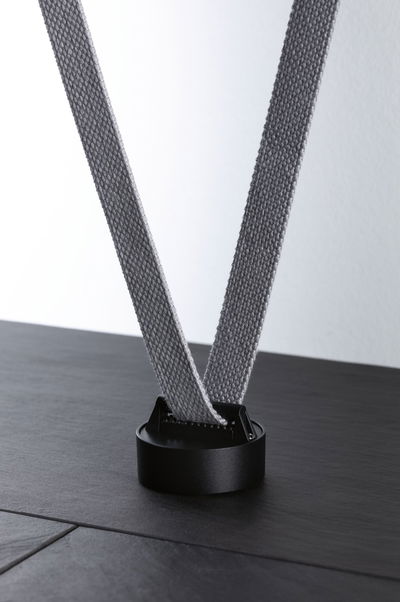 Black round holder with grey fabric strap on dark surface for lighting system accessories
