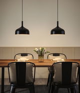 Two black metal pendant lights above wooden dining table set with plates and flower vase
