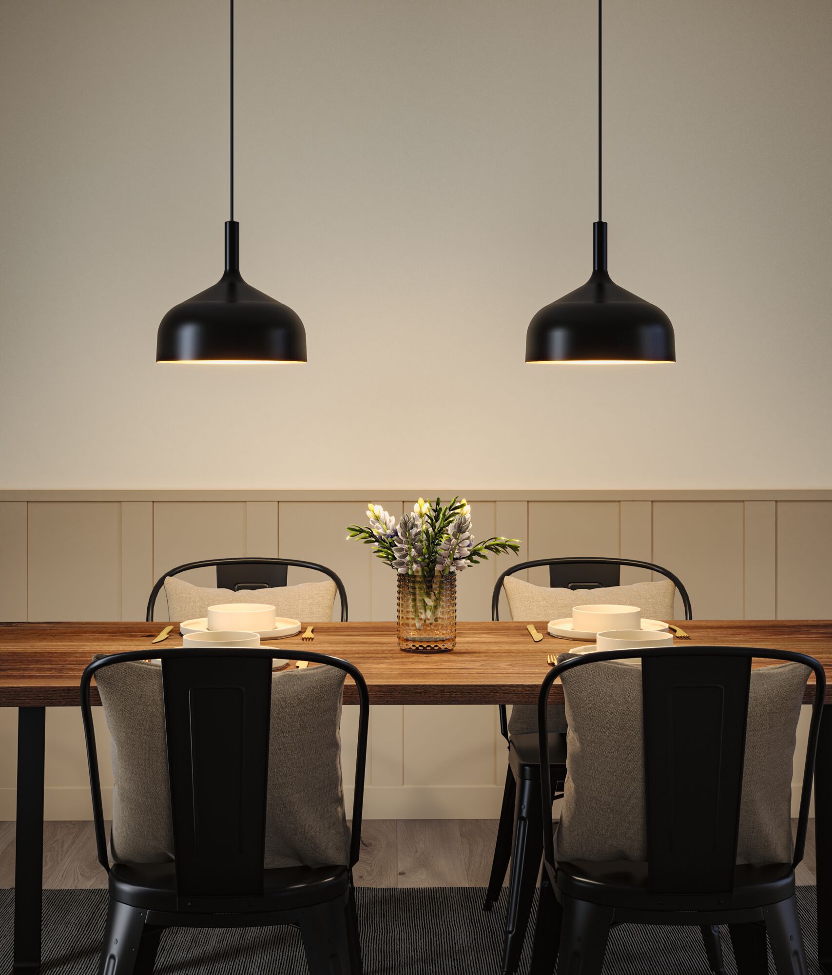 Two black metal pendant lights above wooden dining table set with plates and flower vase